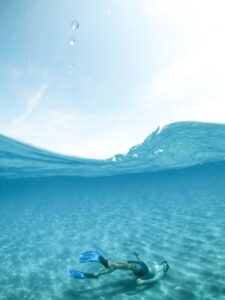 A snorkeler enjoys the crystal-clear waters of Sardinia, Italy, showcasing underwater serenity.